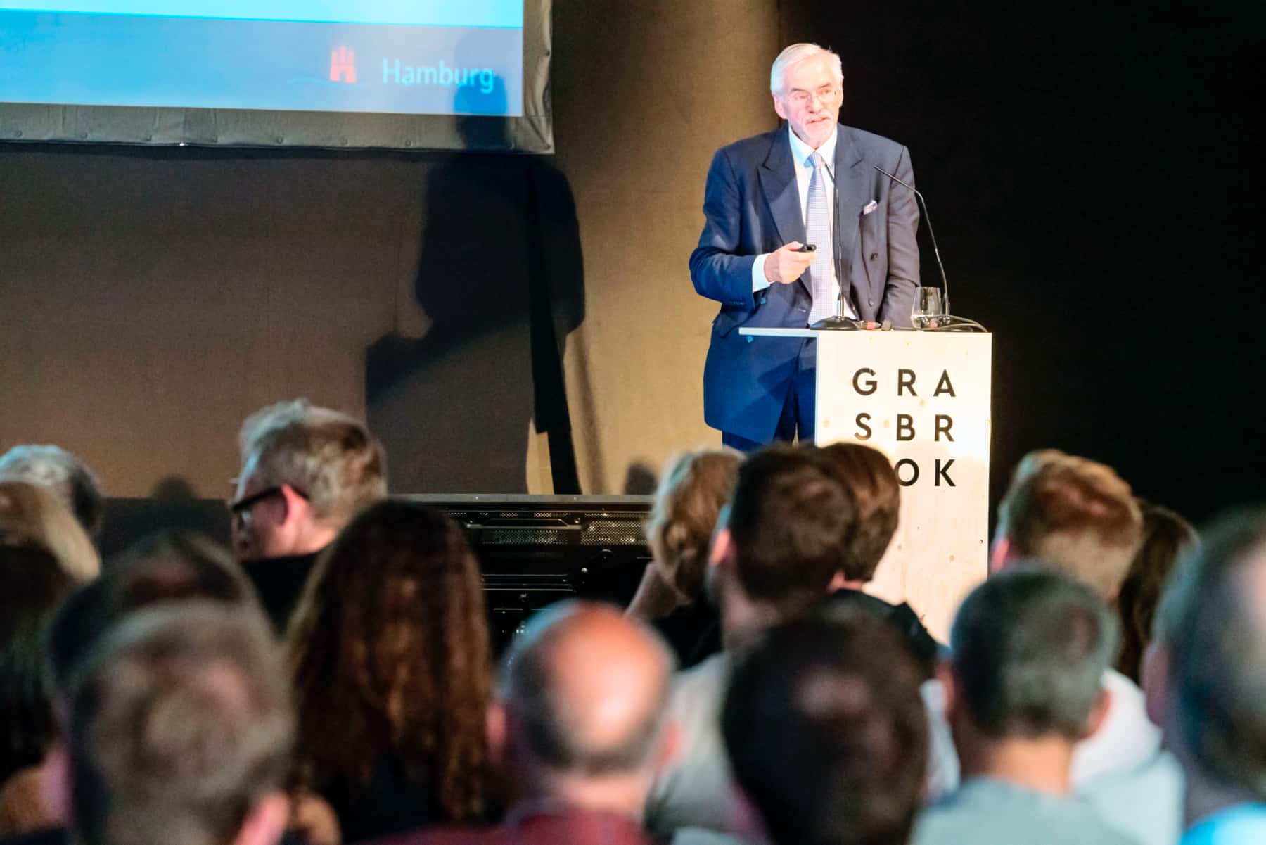 Mann (Jürgen Bruns-Berentelg) gibt Präsentation zum Grasbrook vor Publikum